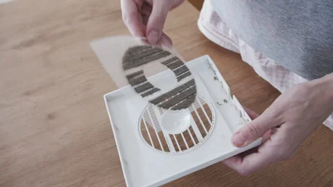 Inspecting Clogged Dust Filter on Air Vent Cover Above Wooden Table Video stock 341397340