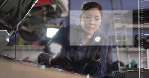 Inspecting engine bay tech in dark coverall leaning over open hood in shop Stock Photos