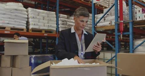 Inspecting manager in blazer and collared shirt using tablet, checking box at Stock Photos