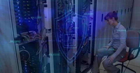 Inspecting tech in light shirt gray slacks leaning into server racks with LEDs, Foto stock
