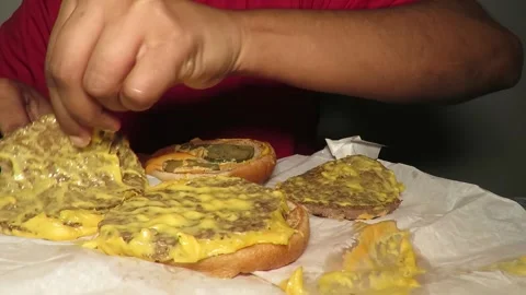 Inspecting a triple beef burger with cheese with sauce and pickle Stock Footage 152603767