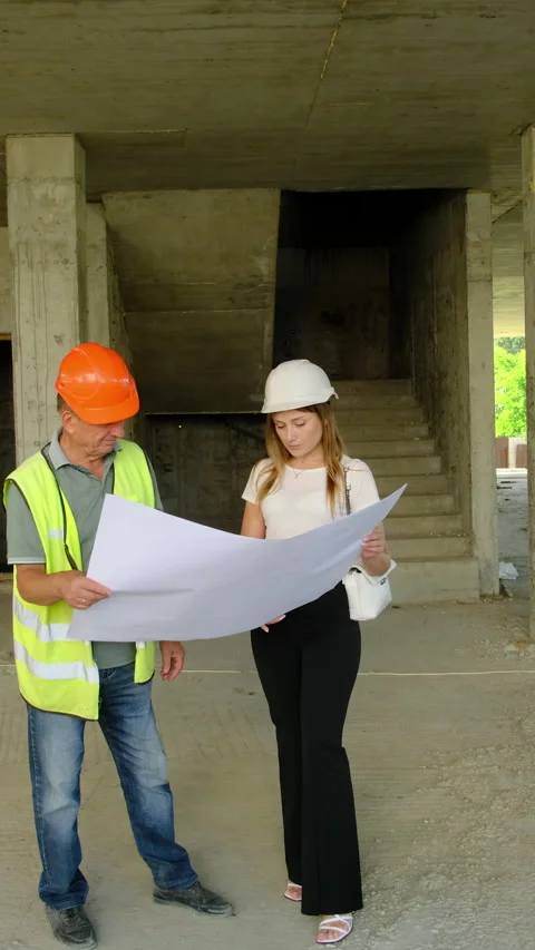 Inspector and builder discuss blueprint holding document in hands Video stock 317622838