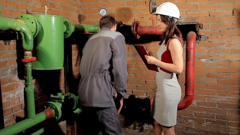 The inspector and the worker check the heating system. The worker tells the 動画素材 76259878