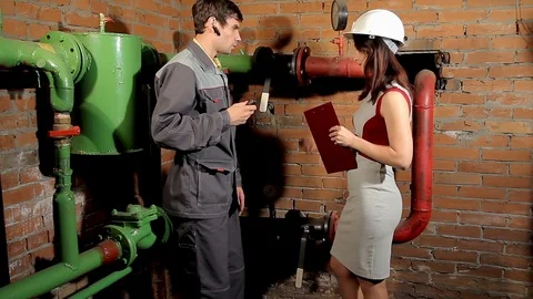 The inspector and the worker check the heating system. The worker measures the Stock Footage 77124410