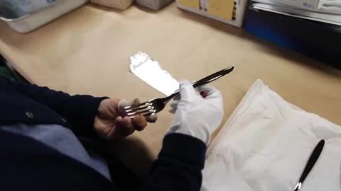 Inspector bending and checking fork under bright desk lamp during quality Stock Footage 340156183