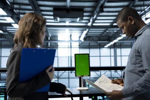 Inspector checking documents in server hub and using greens screen tablet 写真素材