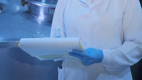 Inspector in gloves and mask writes in papers near huge tank Video stock 145909385