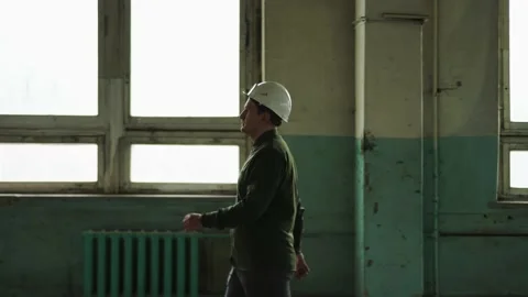Inspector in helmet walks along the corridor of an old building, looks around Stock Footage 152679637