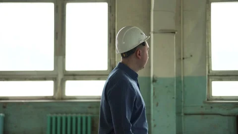 Inspector in helmet walks along the corridor of an old building, looks around Stock Footage 152679724