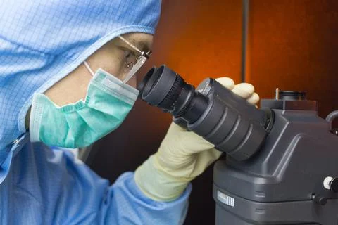 The inspector making incoming check on microscope in clear room. Stock Photos
