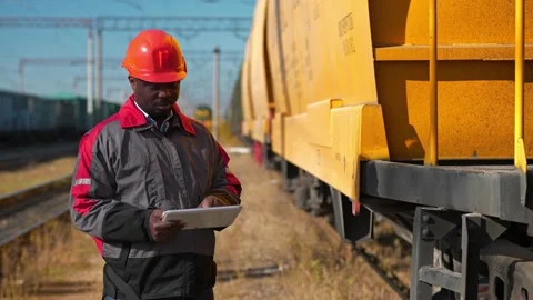 Inspector of wagons at freight train station makes notes in his tablet computer Video stock 177557710