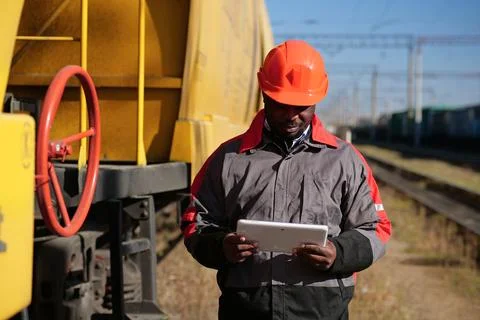 Inspector of wagons at freight train station looks in tablet computer 写真素材