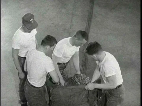An inspector watches as parachute riggers practice packing suspensions lines on Stock Footage 75281902