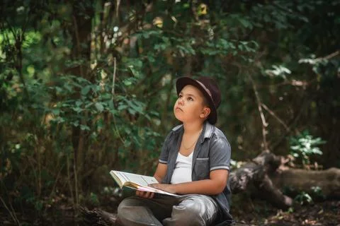 Inspired boy reading an open book looking up Foto stock