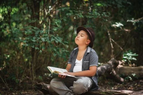 Inspired boy reading an open book has closed his eyes and is dreaming. Foto stock