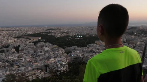 Inspired brunet boy looking at Athens landscape at violet sunset in summer Stock Footage 118939004