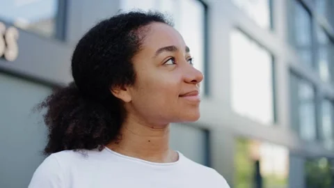 Inspired brunette looking up and smiling tenderly on background of building Vidéo 280466591