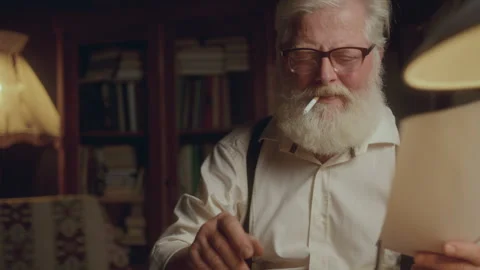 Inspired Elderly Writer Smoking, Reading Paper and Typing Text on Typewriter Stock Footage 285147773