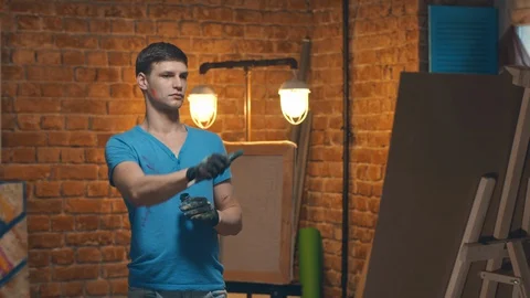 Inspired male painter using easel, creating artwork in modern workshop Stock Footage 129313256