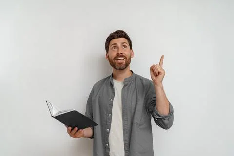 Inspired man holding open notepad and have idea while pointing finger up on Stock Photos