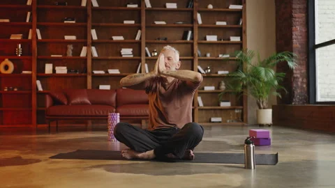 Inspired middle-aged man sitting in lotus pose and meditating at home Stock Footage 340902113