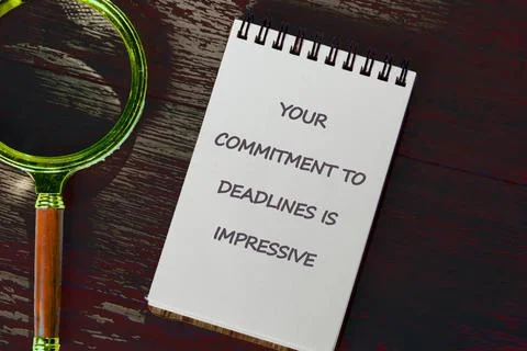 Inspiring note on deadline commitment placed on wooden table with magnifyin.. Foto stock