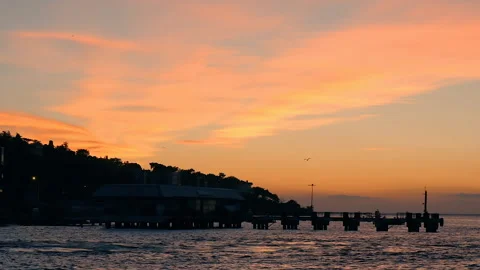 Inspiring sundown light on orange sky over sea surface and silhouette of pier Vidéo 247023409