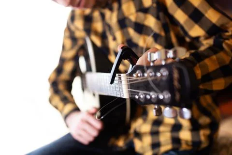 Instal a capodaster, also called capo, for guitar, put across the strings Stock Photos