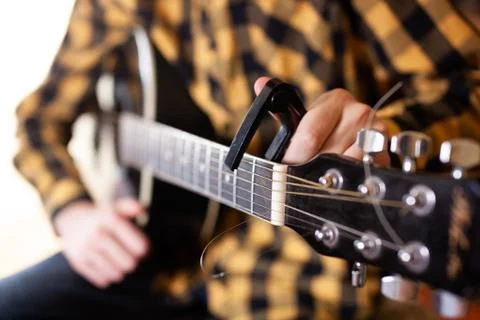 Instal a capodaster, also called capo, for guitar, put across the strings Stock Photos