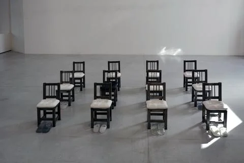 Installation art project with rows of chairs and shoes next to them Stock Photos