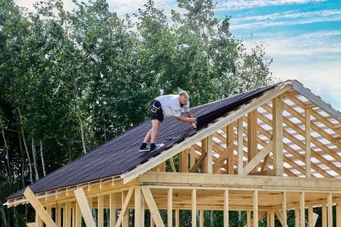 Installation of corrugated bitumen roofing sheets on timber roof structure .. Stockfoto's
