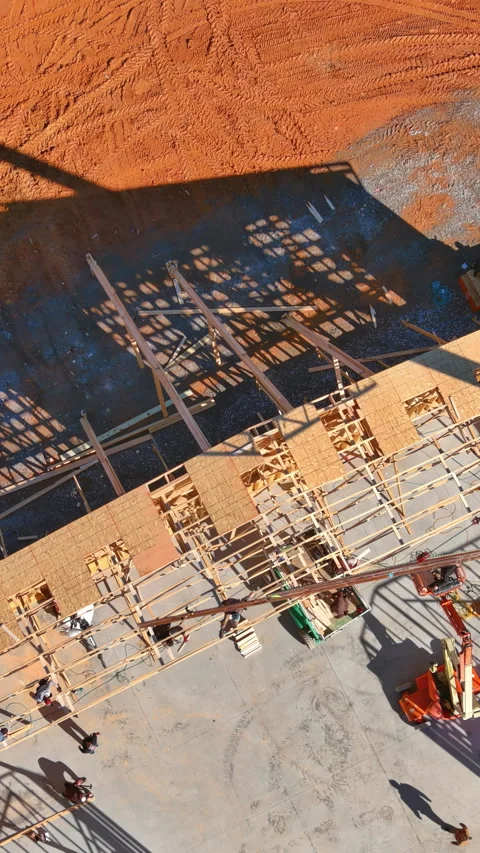 An installation crane is used to install wooden roofing trusses on a new Stock Footage 258776901
