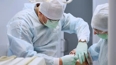 Installation of dental implants in modern dental clinic. Oral surgeon and nurse Stock Footage 261990713