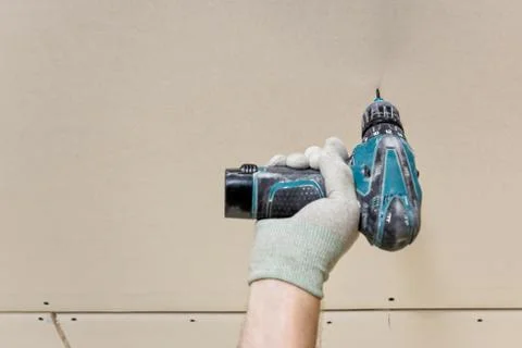 Installation of drywall. Worker's hand with a screwdriver. Stock Photos