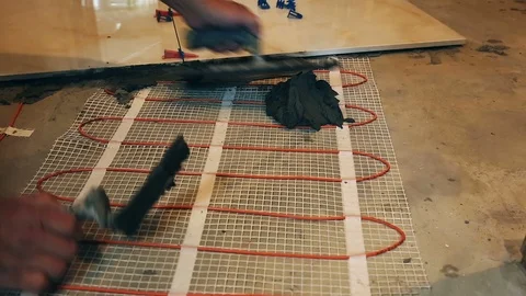 Installation of heated floor. Laying a ceramic or porcelain tile floor close- Video stock 109184733