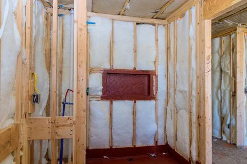 Installation of heating insulation on the wall, amongst wooden beams with sho Stock Photos