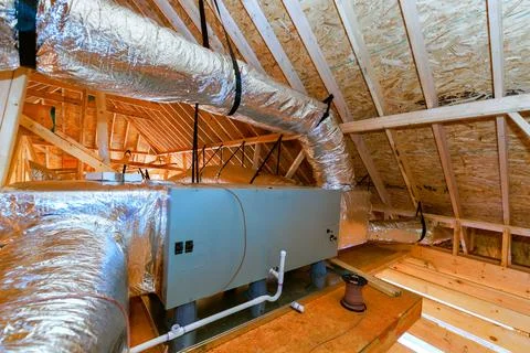 Installation of HVAC system in attic space during home construction process at Stock Photos