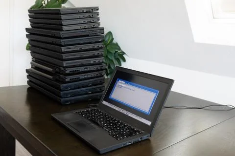Installation of a laptop computer with a stack of several more computers next to Stock Photos