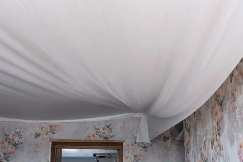 Installation of a modern seamless stretch ceiling in the apartment. Stock Photos