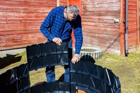 Installation modular compost bin with interlocking panels, farmer assembles.. Stock Photos