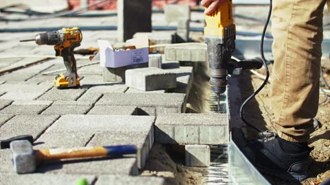 Installation of paving slabs a worker drills a hole Stock Footage 295775116