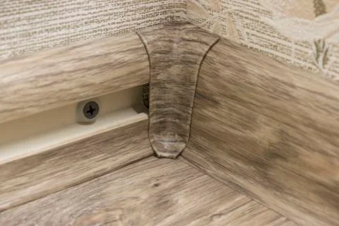 Installation of a plastic skirting on inner corner of floor Stock Photos