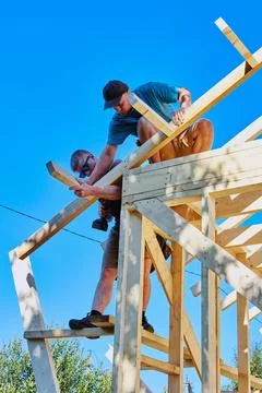 Installation of rafter system of timber frame house, workers fastening raft.. Stock Photos