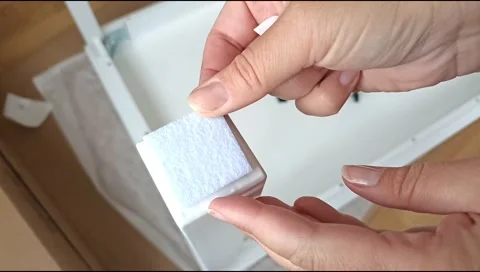Installation of a self adhesive felt pad on a furniture leg to protect flooring Stock Footage 339177282