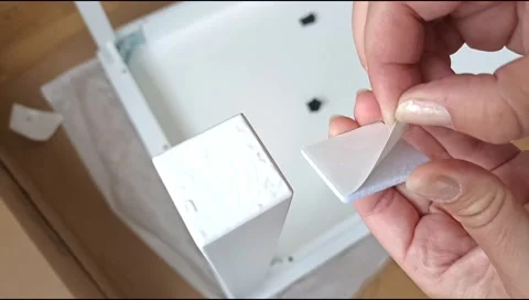 Installation of a self adhesive felt pad on a furniture leg to protect flooring Stock Footage 339177285
