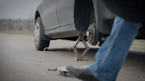 Installation of a spare tire by a man in the middle of the road Stock Footage