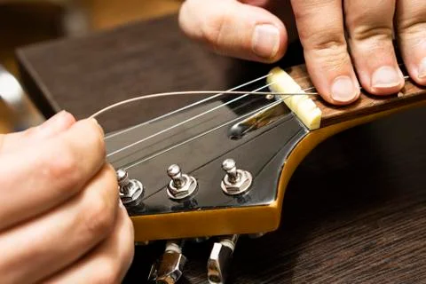 Installation strings of electric guitar through upper threshold on the head of Stock Photos