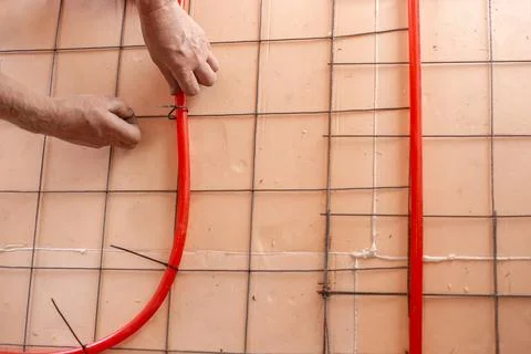 Installation of underfloor heating. A worker fastens pipes for underfloor h.. Stock Photos