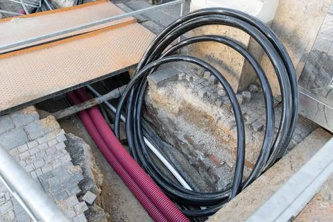 Installation of underground cables and pipes in urban utility trench. Black.. Stock Photos
