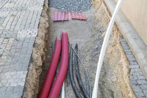 Installation of underground cables and pipes in urban utility trench. Black.. Stock Photos